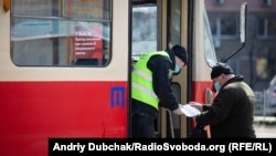 Поліція перевіряє у чоловіка наявність спецперепустки під час посадки до трамваю, Київ, березень 2020 року