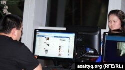 Мужчина у монитора компьютера с загруженной страницей социальной сети Facebook.
