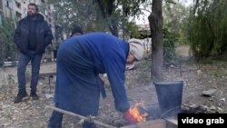 Civilii ucraineni care nu au acces la gaz sau electricitate fac foc în fața blocului la Kosteantinivka (captură de ecran).