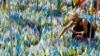 A woman installs a national flag with the name of her husband at a makeshift memorial for fallen Ukrainian soldiers on the Day of Remembrance for Ukraine's Defenders in Kyiv on August 29.