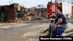 A local resident sits at the site of the fire in central Rostov that damaged or destroyed 123 residential buildings and killed one man. 