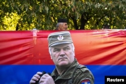 Чоловік проходить повз прапор із зображенням колишнього військового генерала боснійських сербів Ратка Младича
