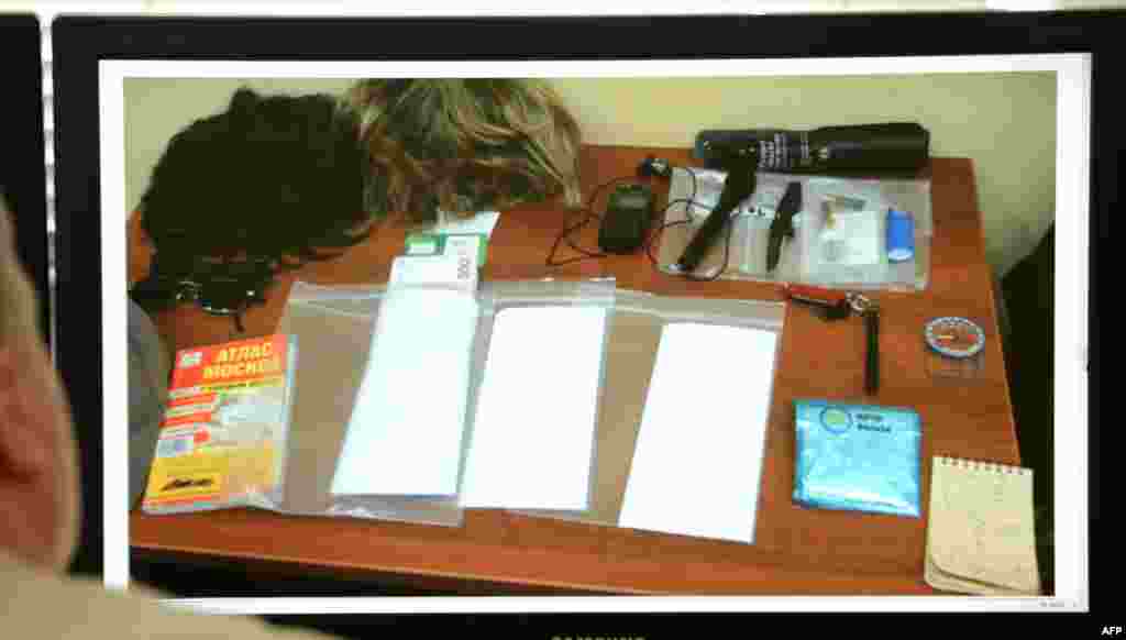 A man looks at a computer screen displaying belongings described as being owned by Ryan C. Fogle in a photo released by the Russian Federal Security Service. The items included two wigs, a compass, a Moscow map, a small knife, and stacks of euro banknotes.