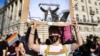 An LGBT protester holds aloft a placard depicting Hungarian Prime Minister Viktor Orban waving a scarf in rainbow colours in front of the parliament building in Budapest during a demonstration against legislation seeking to ban lesbian, gay, bisexual, and transgender content in schools on June 14. 