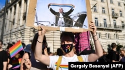 An LGBT protester holds aloft a placard depicting Hungarian Prime Minister Viktor Orban waving a scarf in rainbow colours in front of the parliament building in Budapest during a demonstration against legislation seeking to ban lesbian, gay, bisexual, and transgender content in schools on June 14. 
