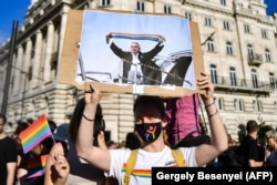 A demonstrator holds a placard showing Hungarian Prime Minister Viktor Orban holding a scarf in rainbow colours, in front of the parliament building in Budapest in June 2021 during a demonstration against the government's draft bill seeking to ban the "promotion" of homosexuality and sex changes.