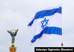 Израильский флаг, прикрепленный к беспилотнику (не виден), развевается рядом с Монументом Независимости во время акции, организованной произраильскими активистами в Киеве, 14 мая 2021 года