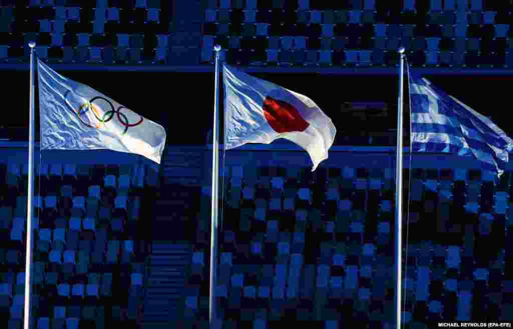 Олимпийский и японский флаги развеваются во время церемонии закрытия Игр в Токио-2020 на Олимпийском стадионе, 8 августа 2021