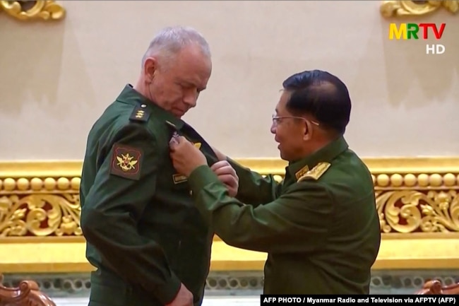 Фото з телевізійної трансляції телебачення у М'янмі, під час якої заступник міністра оборони Росії Олександр Фомін (л) отримує медаль від керівника збройних сил М'янми генерала Мін Аун Хлайна. 26 березня, 2021 року