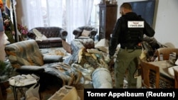 A police officer inspects a section of an Iranian missile that came to rest inside a living room in Rehovot, Israel, on March 20.