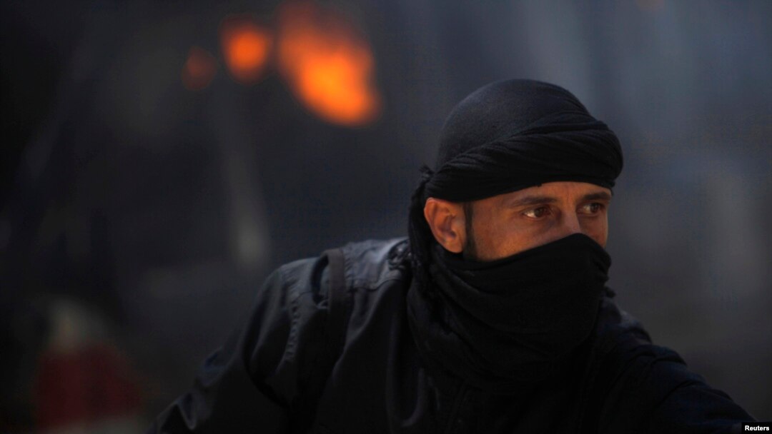 A fighter from the Islamist Syrian rebel group Al-Nusra Front is seen in front of a burning vehicle, caused by what activists said were missiles fired by a government fighter jet, at their base in Raqqa Province, Syria.