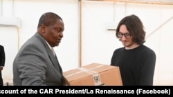  На фотография, оповестена на страницата във Facebook на президента на ЦАР, Дмитрий Ситий (вдясно) предава кутии с медицински консумативи на президента Фостен-Арканж Туадера 