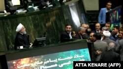 IRAN -- Iranian President Hassan Rohani (Left) speaks at parliament in the capital Tehran on December 25, 2018 as he presents his government's 2019-2020 budget, with a notice below his podium providing Christmas greetings to Christians.