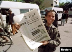 A boy in Kabul selling copies of a newspaper without imagery in October 1996