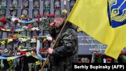 UKRAINE -- An activist of Maidan holding a flag, makes the sign of the cross as he pays a tribute at the Maidan activists memorial also called the "Heroes of the Heavenly Hundred", referring to the people killed during the anti-government demonstration of