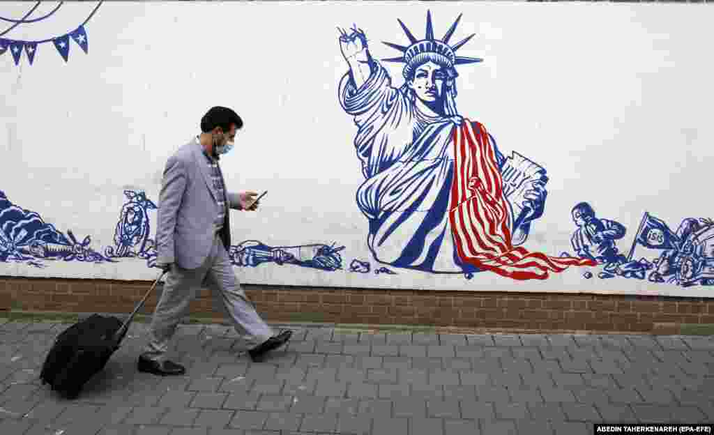 Un bărbat trece pe lângă o pictură murală de pe zidul fostei ambasade SUA la Teheran, care înfățișează Statuia Libertății cu o mână ruptă. Ministerul de Externe din Iran a negat, la 20 decembrie 2021, orice discuție directă cu SUA cu privire la negocierile nucleare, care s-au încheiat la Viena fără semnarea unui acord.&nbsp;