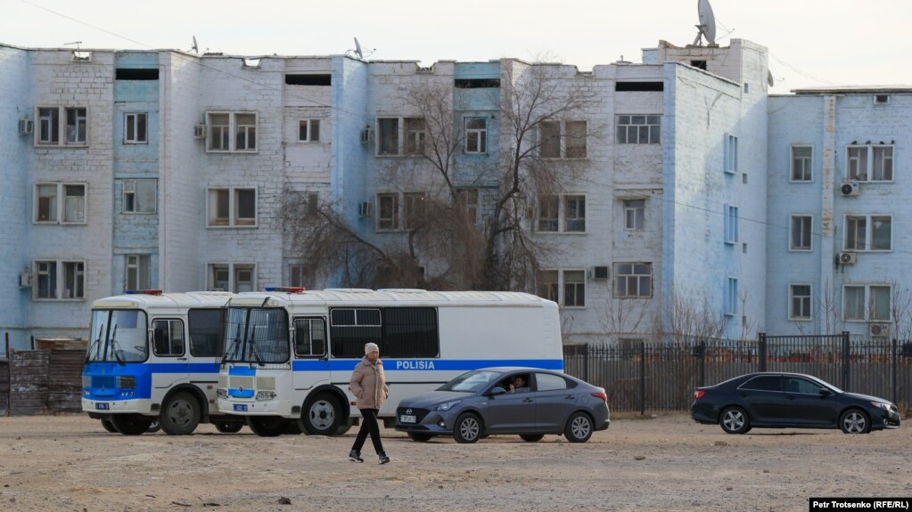 Житель города Жанаозен проходит на фоне припаркованных автобусов полиции. Иллюстративное фото