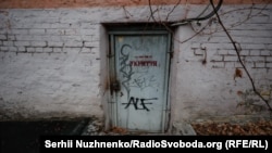 The entrance to a dual-use bomb shelter in Kyiv. The door has the word “shelter” stenciled onto it and the phone number of the person who holds the key.