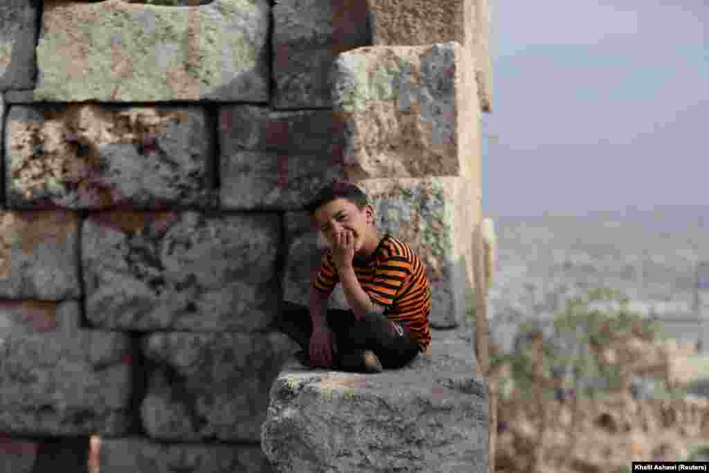 A nyolcéves Baraa&nbsp;Szarjableh egyik romos tornyán üldögél