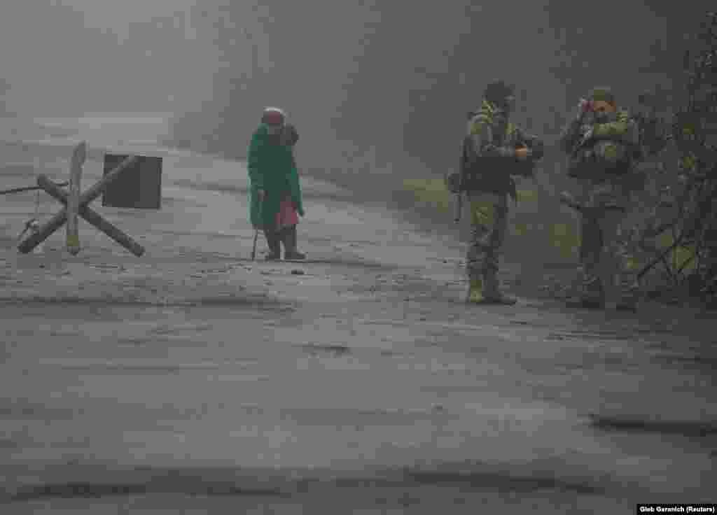 Ukrainian soldiers stand on a street as a local resident walks by in the village of Travneve, near the front line in the Donetsk region.&nbsp;