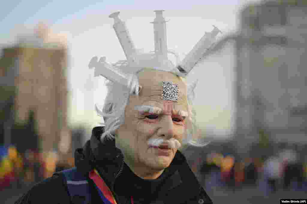 An Romanian protester against COVID restrictions wears a latex mask with syringes attached to it during a rally in front of government headquarters in Bucharest.&nbsp;