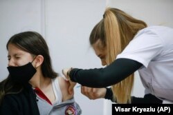 Një nxënëse e shkollës "Eqrem Qabej" në Prishtinë duke u vaksinuar kundër koronavirusit. Të drejtë vaksinimi kundër koronavirusit në Kosovë kanë të gjithë personat 12 vjeç e lart.