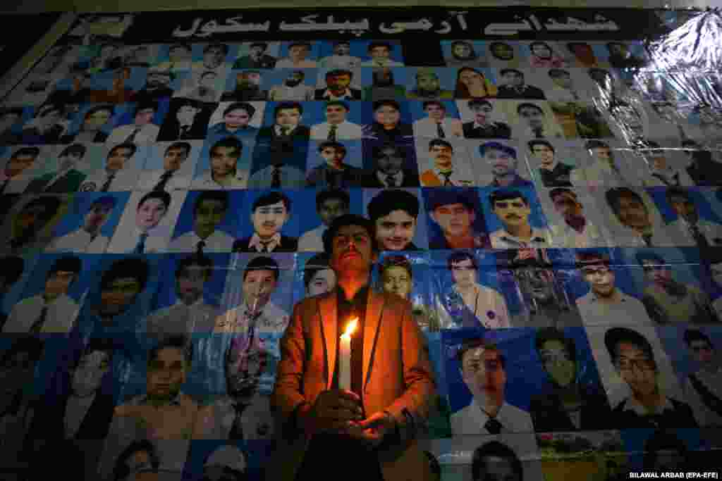 A man holds a candle in front of portraits of victims of the&nbsp;Army Public School (APS) attack in Peshawar, Pakistan, on the seventh anniversary of that massacre, which left 156 people dead.&nbsp;