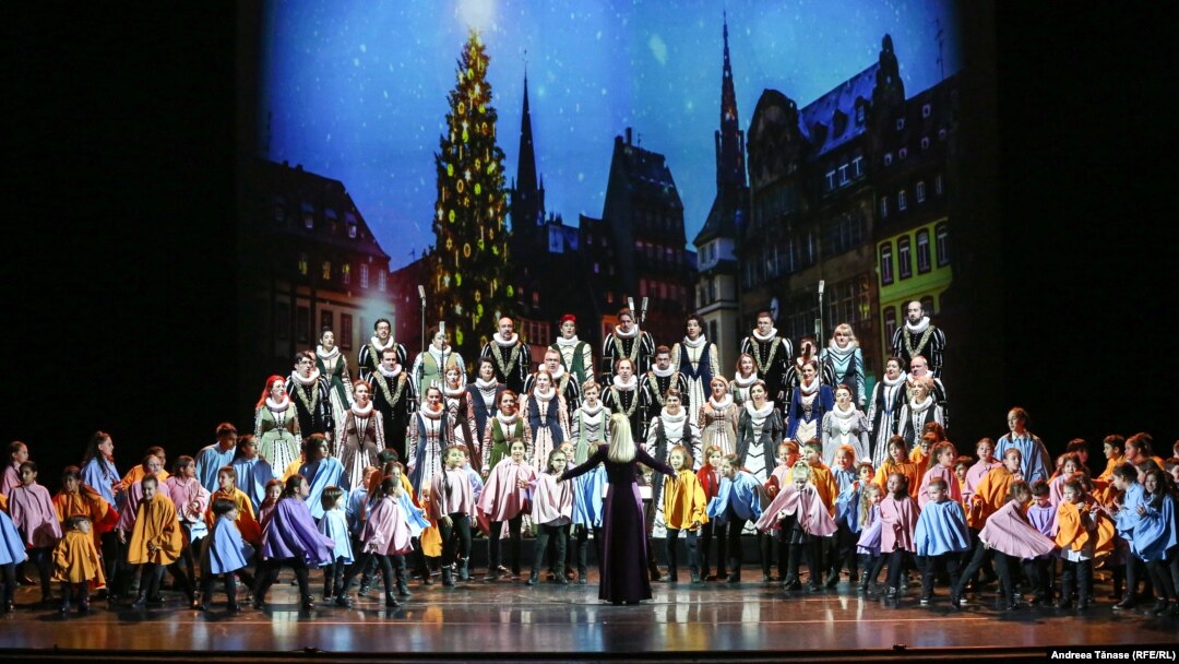 Corul Național de Cameră „Madrigal – Marin Constantin” și copii din Programul Cantus Mundi cântă în timpul spectacolului „Pe drumul Crăciunului”, pe scena Operei Naționale din București. 