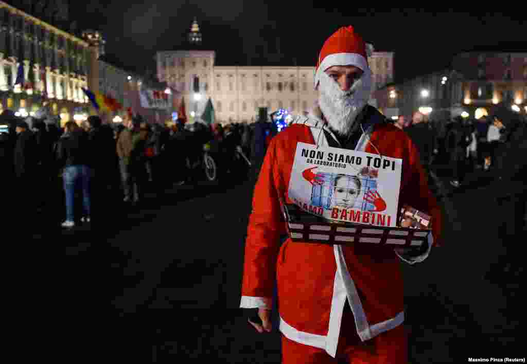 &bdquo;Nem laboratóriumi egerek vagyunk, hanem gyerekek&rdquo; &ndash; olvasható a Mikulásnak öltözött tüntető nyakában Torinóban december 18-án