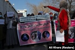 Afgán nők transzparenseket és plakátokat tartanak egy tüntetésen, amelyen a nőkre vonatkozó tálib korlátozások ellen tiltakoznak Kabulban 2021. december 28-án