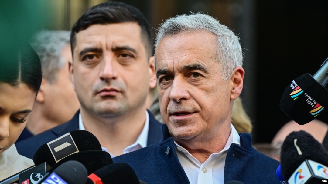 Calin Georgescu (right) talks to the media after filing his candidacy for the Romanian presidential election on March 7. His ally, far-right leader George Simion (left) is in the background. 