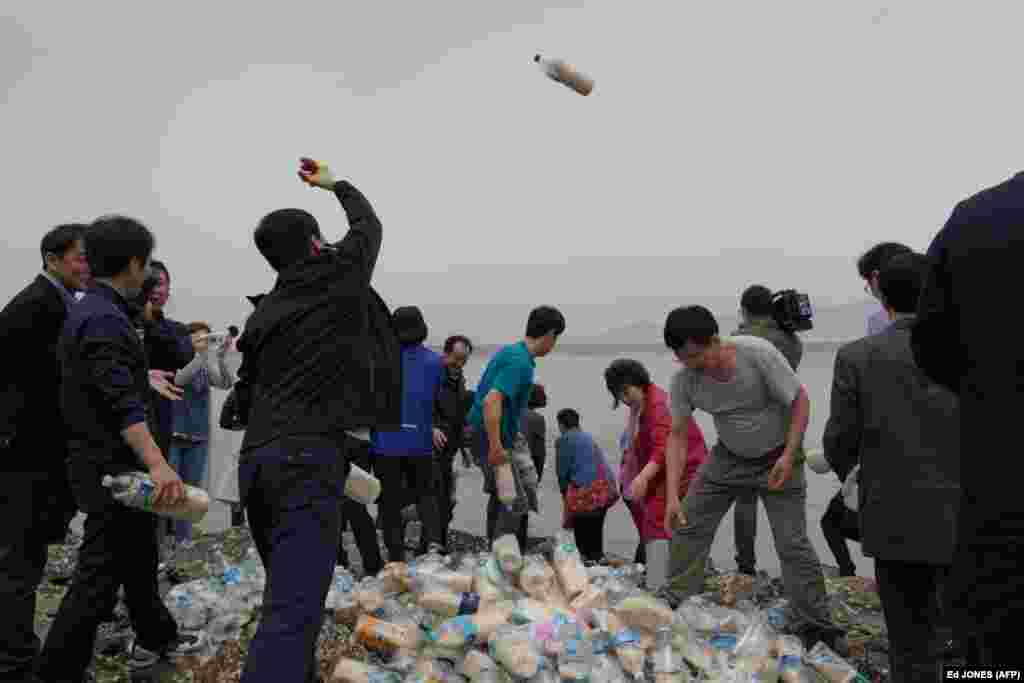 Bottles containing rice, money, and USB sticks are thrown into the sea by North Korean defector activists on Ganghwa island, west of Seoul, on May 1. The defectors have been throwing hundreds of bottles filled with food, cash, medicine, and memory sticks into the sea twice a month for more than two years. South Korean coast guards have told them the bottles are often retrieved by North Korean fishing boats. (AFP/Ed Jones)