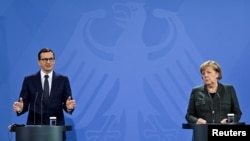 Polish Prime Minister Mateusz Morawiecki (left) and German Chancellor Angela Merkel address a joint press conference after talks in Berlin on November 25.