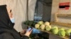 Клиент овощного ларька записывает телефонный номер продавца, чтобы оплатить покупки. Номер указан на стене. Алматы, 25 февраля 2021 года.