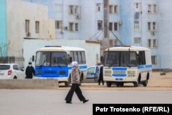 Женщина идет по центральной площади Жанаозена мимо полицейских автобусов. Мангистауская область, 16 декабря 2021 года