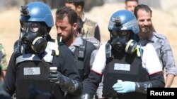 UN chemical weapons experts wearing gas masks carry samples from one of the sites of an alleged chemical weapons attack in the Ain Tarma neighbourhood of Damascus in August.