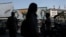 People walk past a mural depicting the late leader of the Islamic Revolution, Ayatollah Ruhollah Khomeini, and the late Iran's Supreme Leader Ayatollah Ali Khamenei, on a street in Tehran