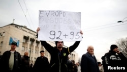 An anti-government protester holds a placard reading, "Europe, you owe us, do you remember 1992-1995?" during a protest in Sarajevo.