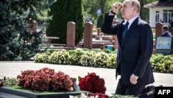  Președintele rus Vladimir Putin își face cruce după ce a depus flori la cimitirul memorial consacrat victimelor de la Beslan.