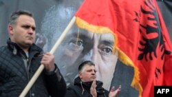 A man waves an Albanian flag next to a banner of former Kosovar Prime Minister Ramush Haradinaj during a protest staged by Kosovo war veterans' associations in support of the ex-guerrilla commander who is currently being detained in France. 
