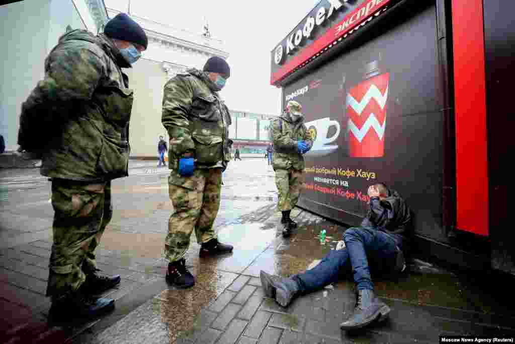 Cossacks wearing protective masks surround a man lying on the pavement as they patrol the streets in Moscow. (Moscow News Agency via Reuters/Sergei Vedyashkin)