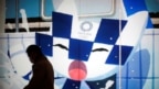 Японец в маске проходит мимо экрана с изображением Мирайтовы – одного из двух талисманов Олимпийских игр 2020 года. Токио, 22 января