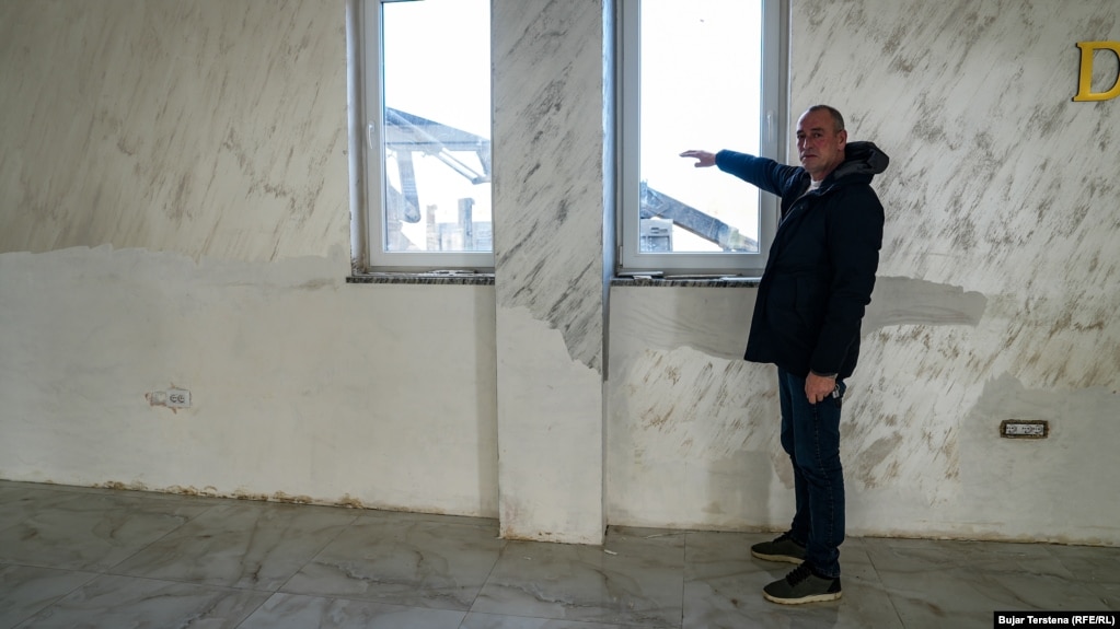 Berisha thotë për REL-in se niveli i ujit brenda restorantit të tij kishte mbërritur deri në gjysmë të dritares, siç tregon ai me dorë në këtë fotografi.“Po presim të bëhet më mirë dhe të ndreqen gjërat, e jo të vuajmë gjithmonë”. Ai kërkoi nga autoritetet të “ndërmarrin masa” për pastrimin e shtratit të lumit Drin.