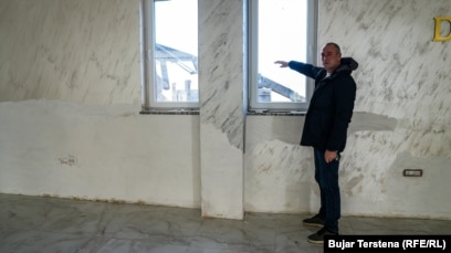 Berisha thotë për REL-in se niveli i ujit brenda restorantit të tij kishte mbërritur deri në gjysmë të dritares, siç tregon ai me dorë në këtë fotografi.“Po presim të bëhet më mirë dhe të ndreqen gjërat, e jo të vuajmë gjithmonë”. Ai kërkoi nga autoritetet të “ndërmarrin masa” për pastrimin e shtratit të lumit Drin.