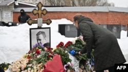 Жена поставя цветя на гроба на руския опозиционен лидер Алексей Навални в Москва на втората годишнина от смъртта му. 16 февруари 2026 г.