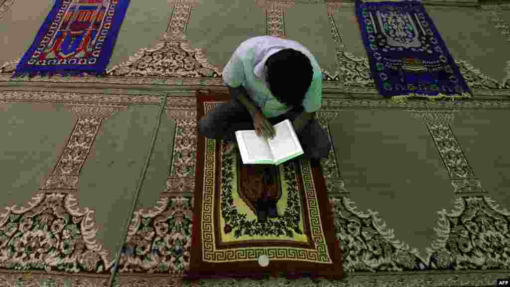 A man reads the Koran on a prayer mat at a mosque in Baghdad&#39;s northeastern suburb of Sadr City on July 16. (AFP/Ahmad Al-Rubaye)