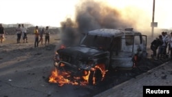 People watch a vehicle which belonged to Shi'ite Muslim rebels burn during clashes in Aden on March 26.