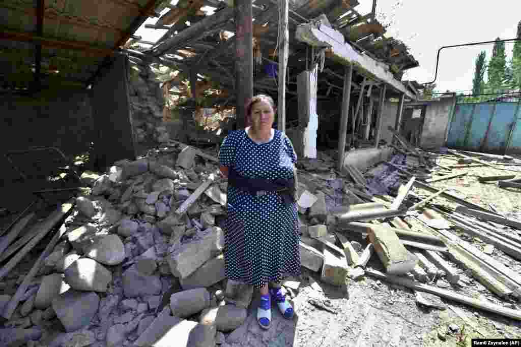 A woman stands in front of her damaged home in Azerbaijan&#39;s northern Tovuz region on July 16 after cross-border fighting resumed between Armenian and Azerbaijani forces.