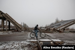 Un localnic cu bicicleta, trecând pe lângă un pod distrus, în apropierea orașului strategic Pokrovsk, unde au loc cele mai intense lupte de pe frontul din estul Ucrainei, 19 decembrie 2024.