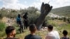 People gather around remnants of a missile stuck in the ground found in Kifl Haris village, near Nablus in the Israeli-occupied West Bank, on March 24.